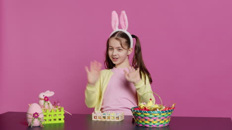 energetic young girl with adorable bunny ears waving in studio