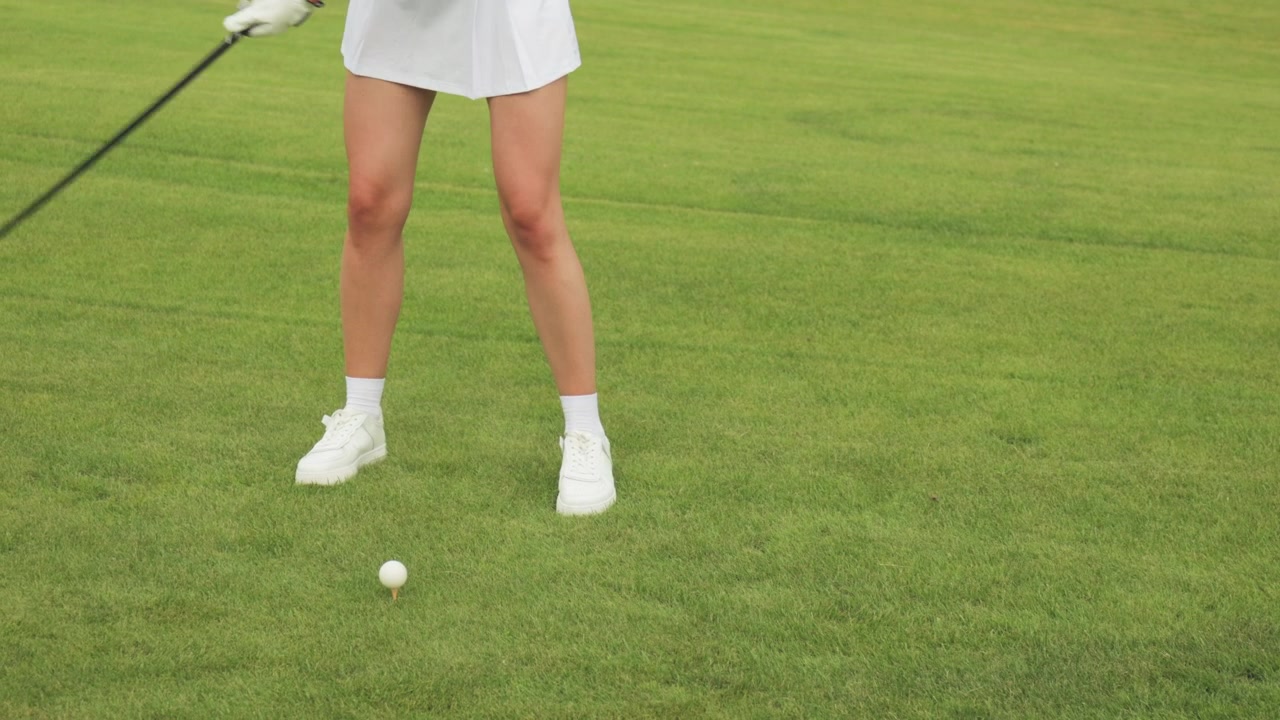 Primo piano di una donna che colpisce una pallina da golf con un driver su un campo verde