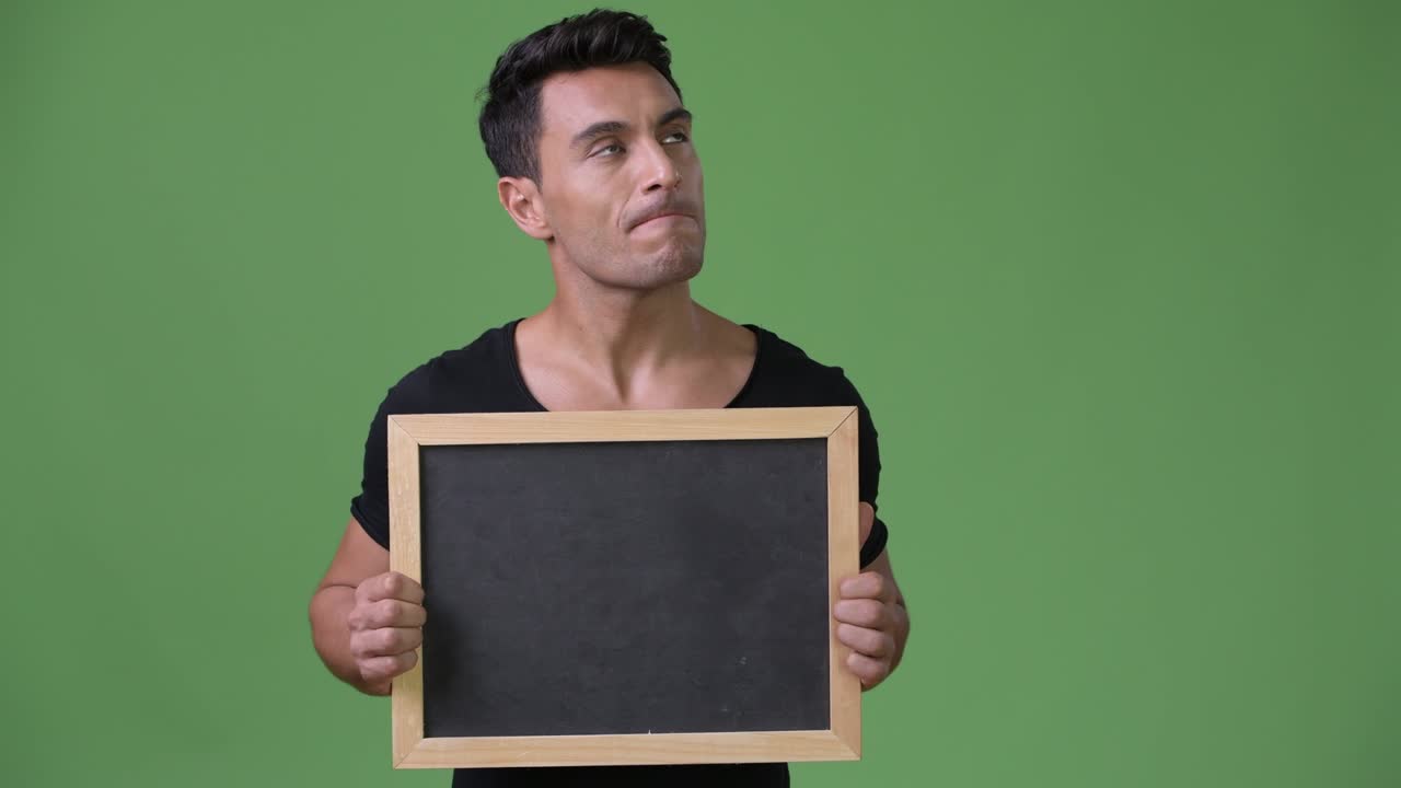 joven y guapo hombre hispano contra un fondo verde