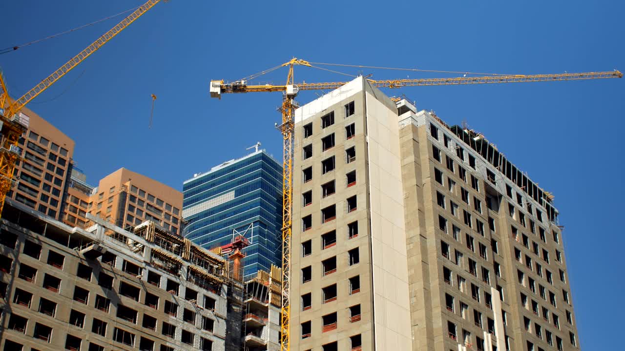 panorama desde el cielo azul claro a los edificios en construcción con grúas en el día de verano