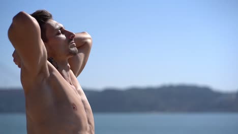 muscular shirtless man with closed eyes training at riverside