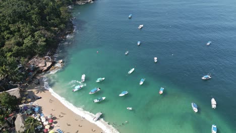 Boats anchored in clear green waters off coast of Playa Mismaloya Mexico, aerial bird&#039;s eye view