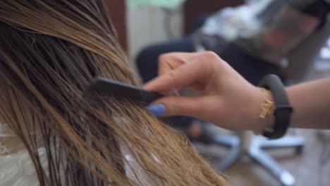 woman getting her brown hair dressed in hair salon