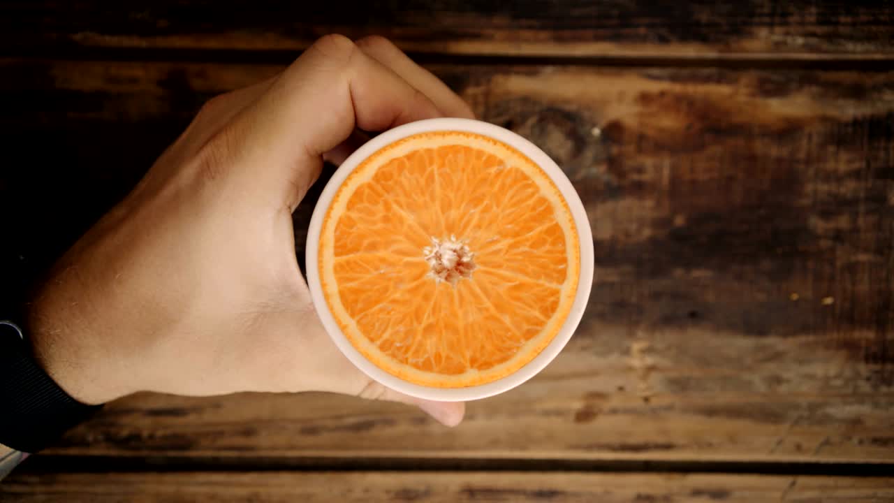 bucle de vista superior de la mano que sostiene la taza con naranja en el interior