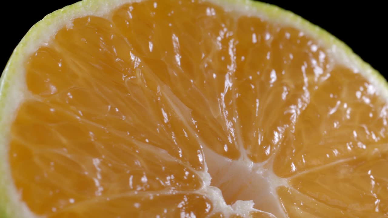 Video di mandarino affettato rotante su sfondo nero.