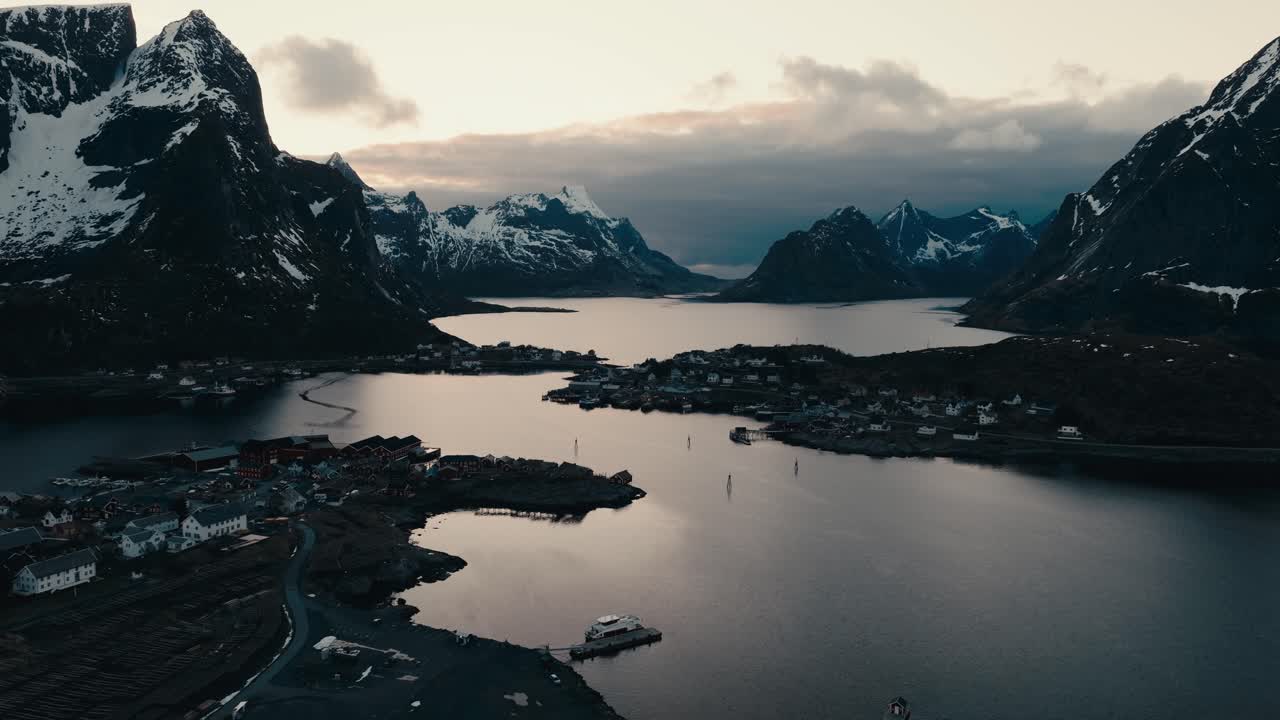 Aerial View Of Reine, Lofoten, Norway - Snow-capped Mountains And Village On Island Of Moskenesoya At Sunset.
