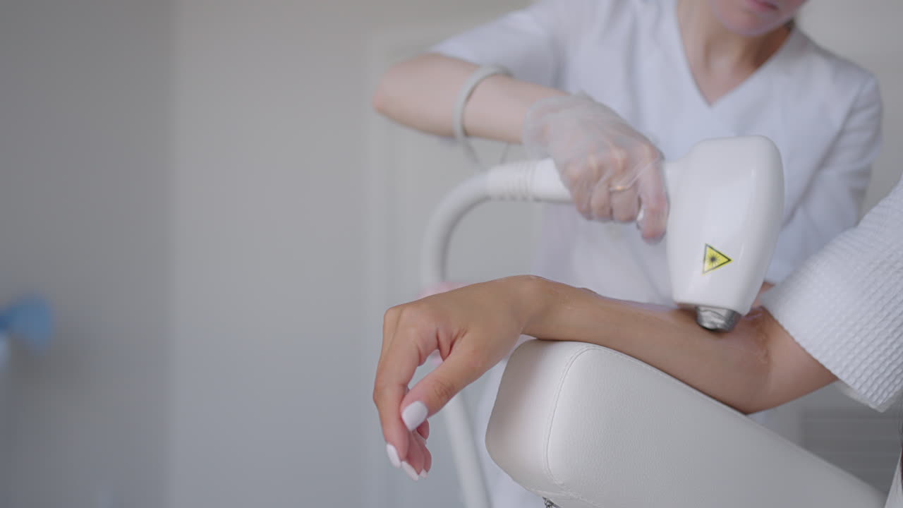 손에 머리카락을 제거하는 절차. 다이오드 레이저 트래킹 움직이는 카메라에서 레이저 머리카락 제거. 여성 미용학자가 여성 손에 레이저 머리카락 제거 젤을 적용합니다. photoepilation 신체 관리 개념.