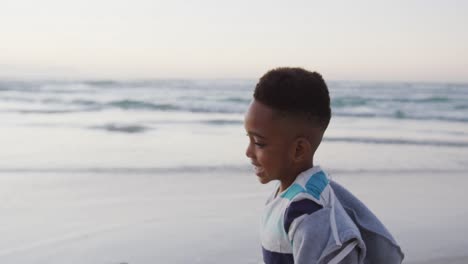 happy african american boy running alone on sunny beach