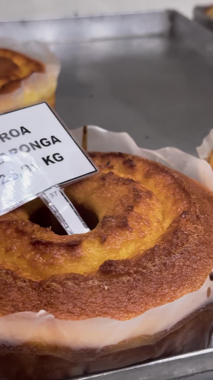 4K vertical close-up of fresh broas on display at a bakery in Viçosa, Minas Gerais. The golden, rustic texture highlights the artisanal quality of this traditional Brazilian baked treat.