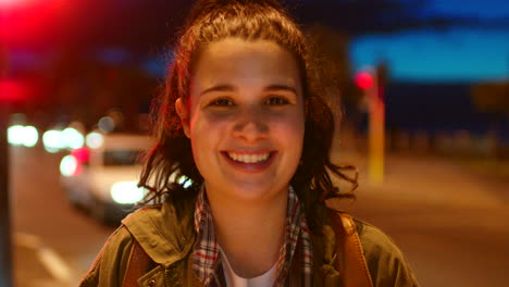 mujer sonriente en una calle de la ciudad por la noche