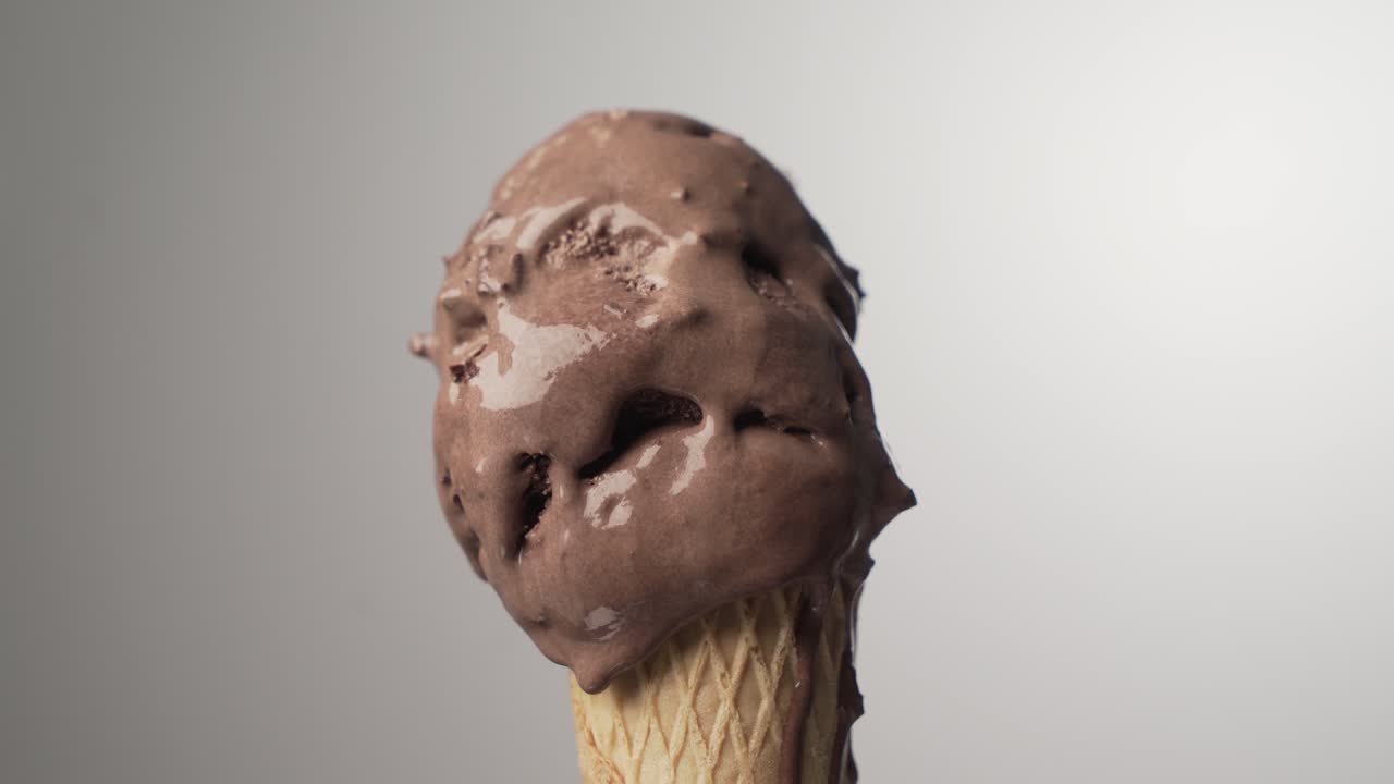 Cono gelato al cioccolato che si scioglie gradualmente su sfondo isolato. Time lapse 4k
