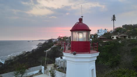 close plane, in orbital trajectory to right, around small lighthouse, with view of sun at sunset