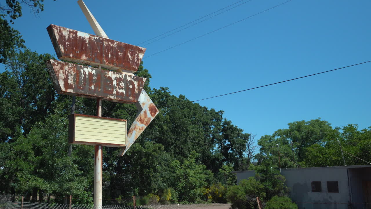 rotativa derecha toma de un cartel de una tienda retro oxidada en frente de un patio de madera abandonado en un día soleado brillante