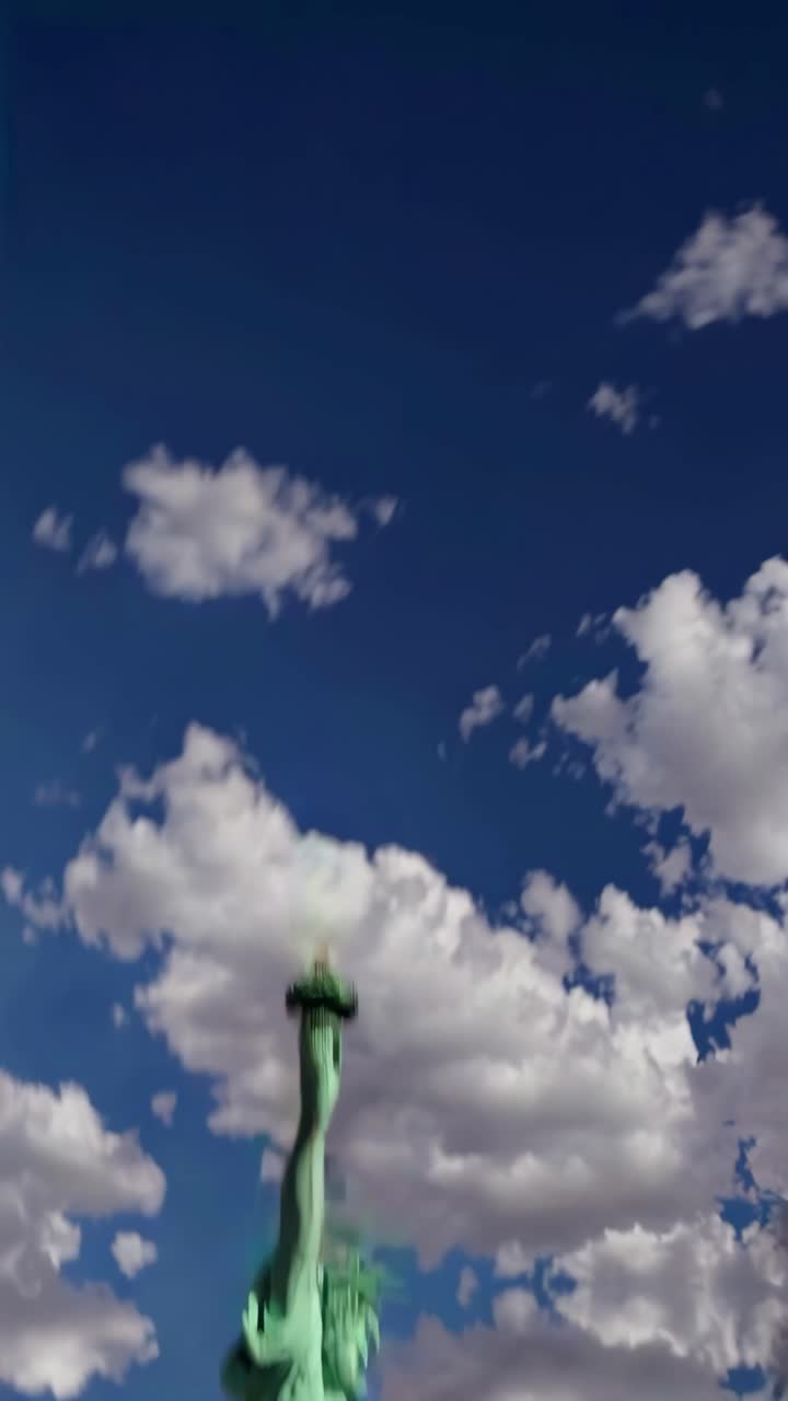 Dramatic low-angle shot of the Statue of Liberty against a vibrant blue sky with clouds