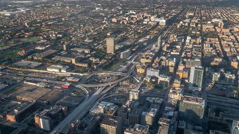 panoramic aerial timelapse view of traffic moving swiftly through a major highway or expressway interchange near downtown chicago with high rise mid and low rise buildings beyond.