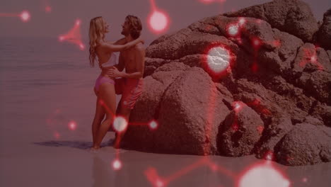 couple embracing by large rocks at beach with red light animation overlay