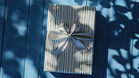 a gift box with a blue ribbon on a blue wooden table