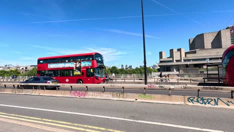 bus travels across london bridge in sunny weather