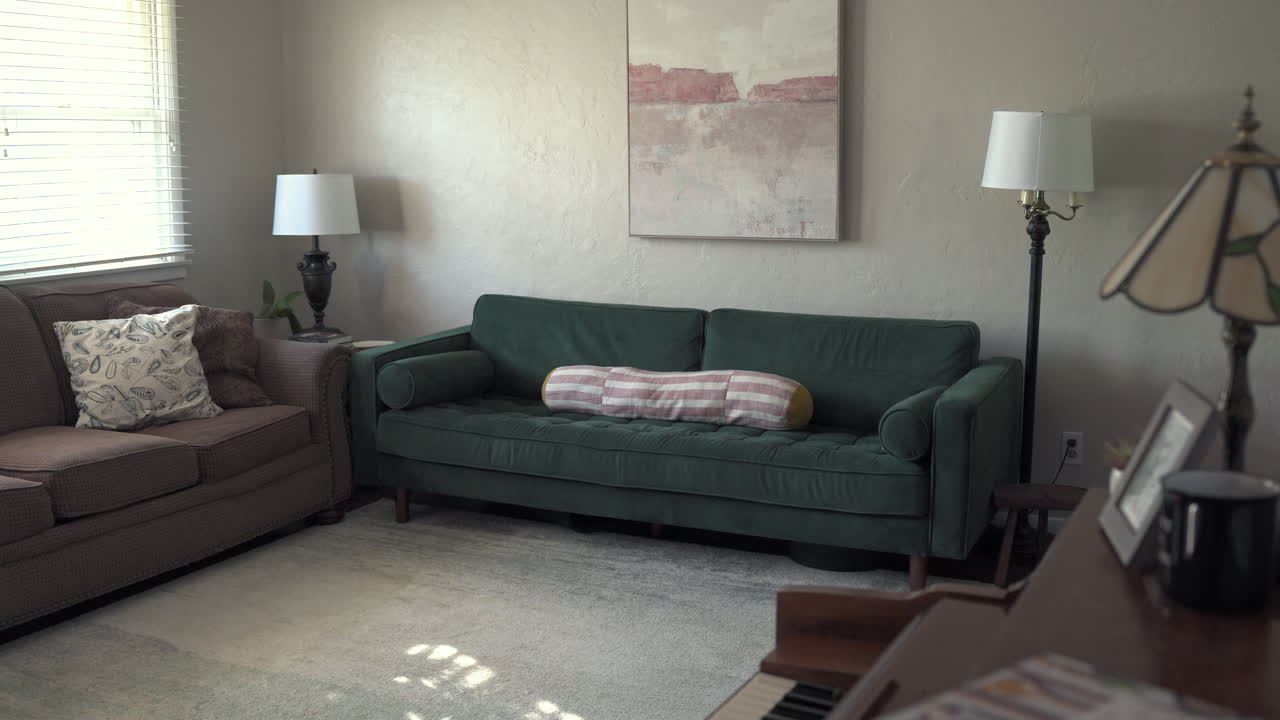 A sliding shot to the left of a modern living room featuring a green couch. The parallax effect adds depth and smooth motion to the scene.