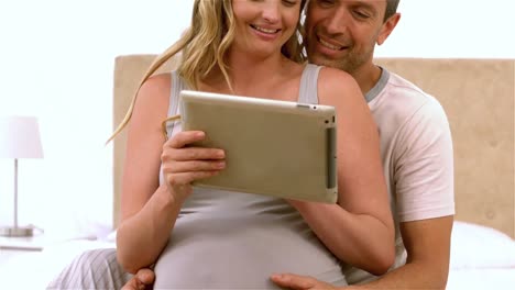 Happy-future-parents-using-tablet