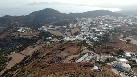 vista de avión no tripulado en grecia volando sobre una iglesia blanca en una colina con una casa blanca griega ciudad frente al mar azul en una montaña