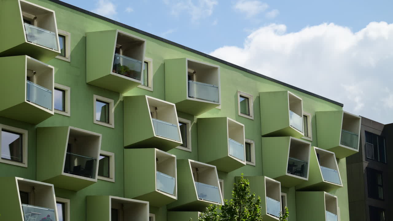 Facciata di edificio green con balconi e finestre geometrici moderni e distintivi sotto un cielo blu