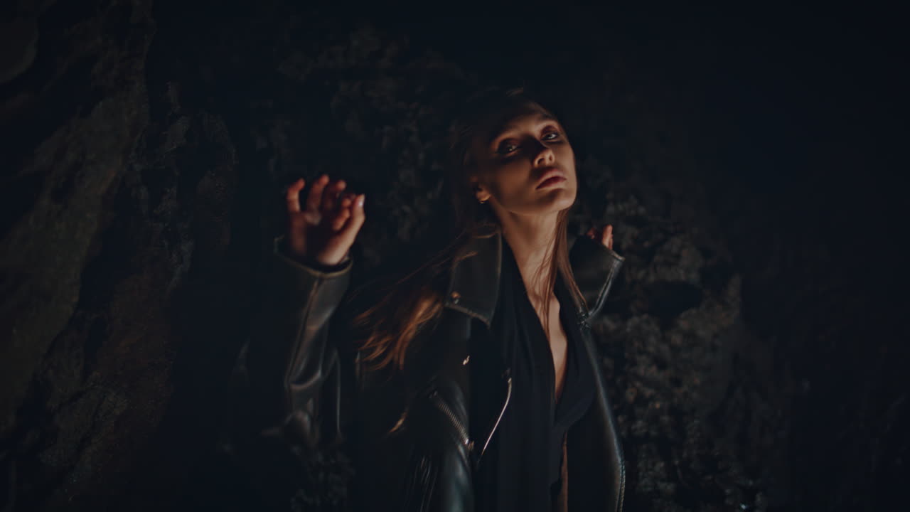 파티 춤을 추는 여자 어두운 바위 해변 클로즈업. 여자 클럽버가 손을 움직여 포즈를 취합니다.