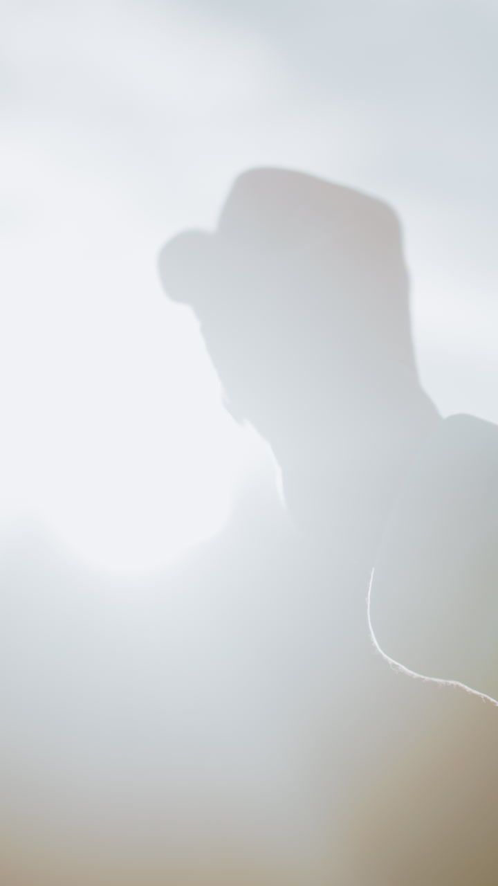 Donna illuminata dal sole mostra forza con un gesto, scena all'aperto che immortala una donna determinata con il pugno alzato, silhouette retroilluminata di una donna che dimostra resilienza e forza interiore all'aperto