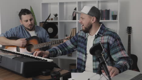 young male musicians singing and playing guitar and electric keyboard at home