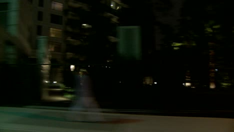 a car travels along a street at night in century city los angeles as seen through the side window 7