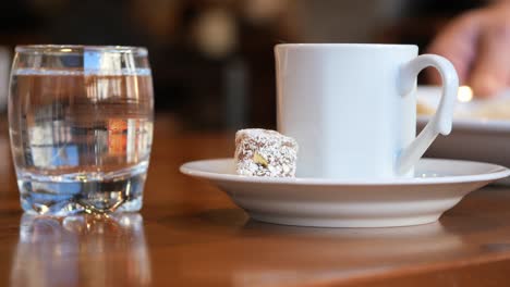 una taza de café turco con delicias turcas y un vaso de agua en una mesa de madera
