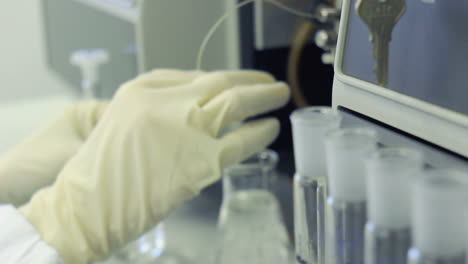 químico trabajando con un frasco de vidrio. fila de tubos de ensayo en un laboratorio médico