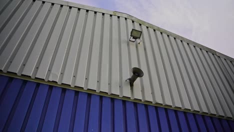 white-blue-roof-of-a-warehouse-with-speaker-and-light-on-it