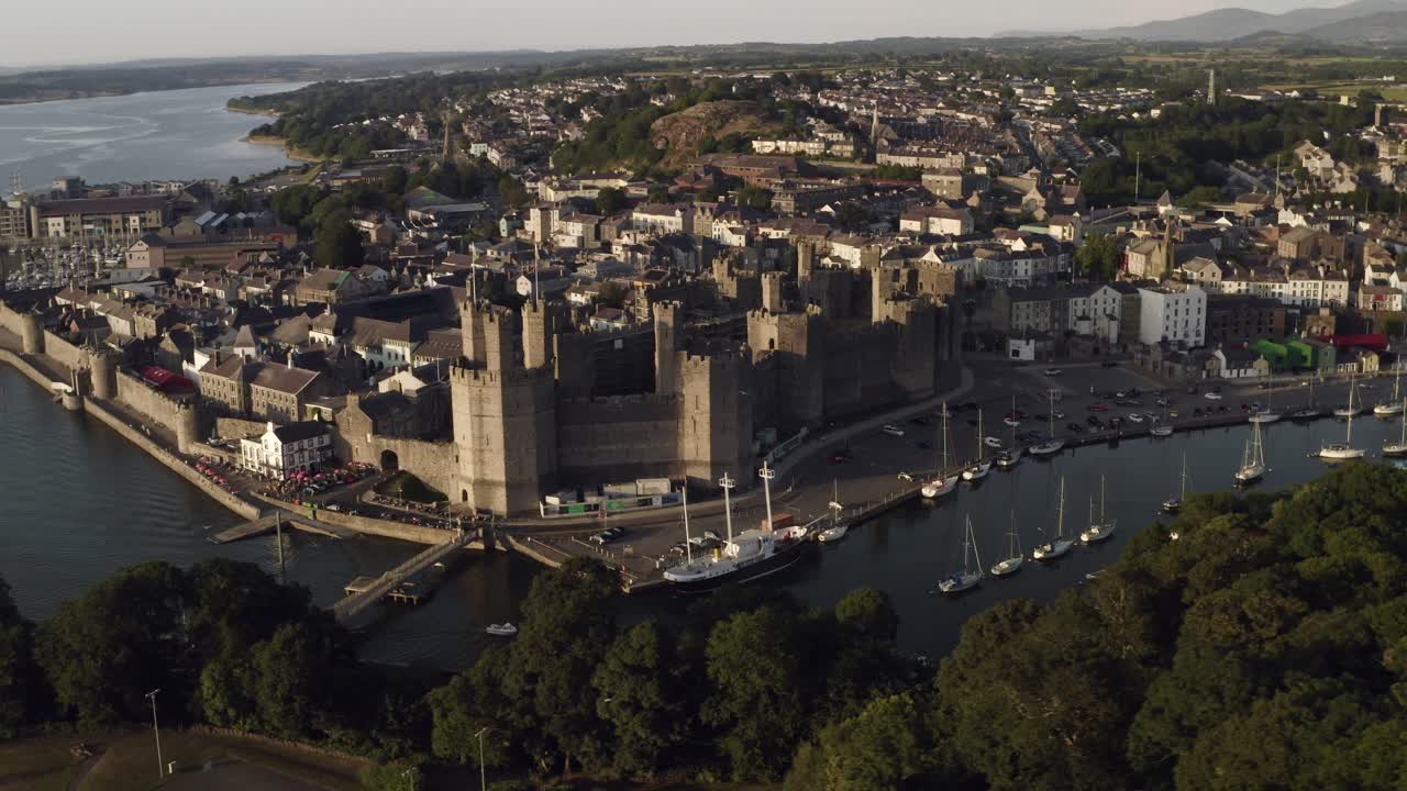 Droneoptagelse af Caernarfon Slot i aftenlys, viser også Menai-strædet, Gwynedd, Nordwales, Storbritannien