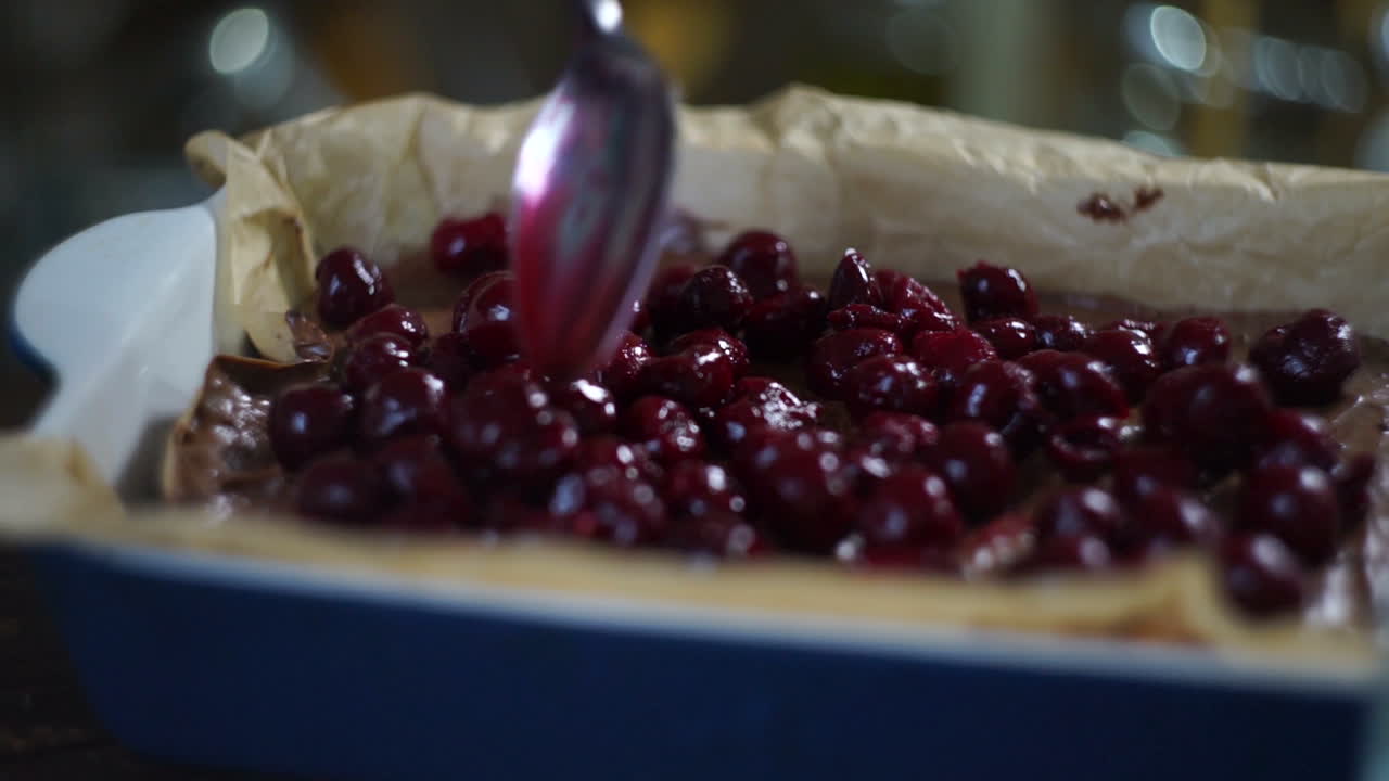 ⁇ 가락으로 초콜릿 케이크에 체리를 첨가하는 요리사. 케이크 재료