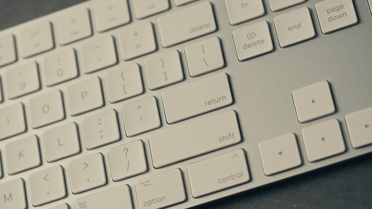 Finger Pressing Return Key on a White Keyboard