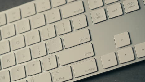 presionando con el dedo la tecla de retorno en un teclado blanco
