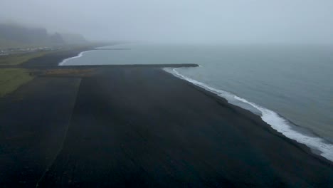 drone soars over vik's black sand beach, where fog enshrouds crashing waves, unveiling a hauntingly beautiful scene in sharp 4k detail