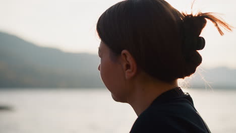 lady throws stones into lake on sunny day. relaxation at spending time in nature with breathtaking views of rolling mountains in autumn. sad moments from lonely life