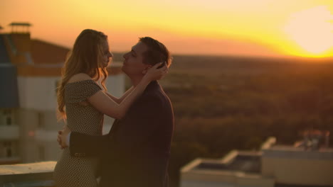 Hugging-standing-on-the-roof-at-sunset.-Summer-roof-at-sunset.-A-man-with-a-girl-came-on-a-romantic-date-on-the-roof.