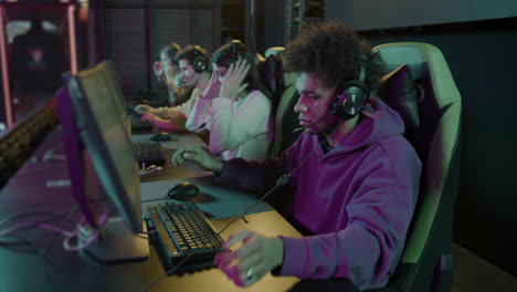 team of four cybersport gamers wearing headphones and playing video games in a gaming club