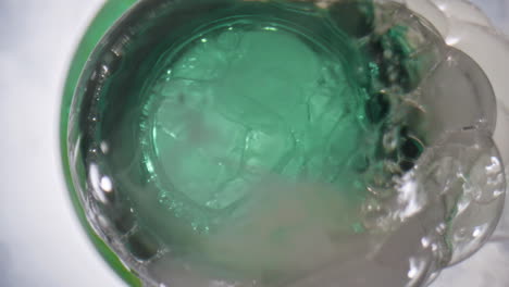 botella de espuma de cerveza fría de primer plano. licor de lúpulo espumando fuera del frasco abierto