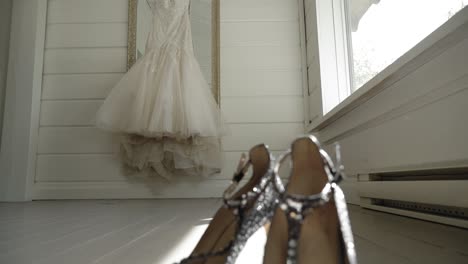 slow motion pan capturing a beautiful bridal gown and a pair of elegant crystal high heals in a well lit sunny white room at le belvédère in wakefield, quebec, canada