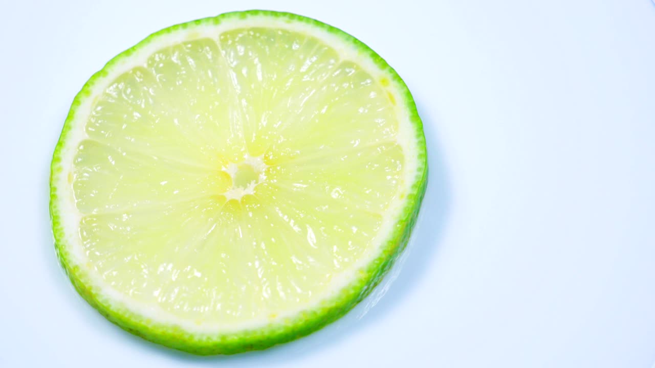 una rebanada de limón verde está girando lentamente en el estudio con los detalles.