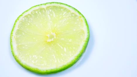 una rebanada de limón verde está girando lentamente en el estudio con los detalles.