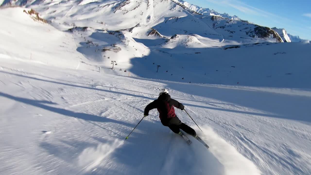 Curve ad alta velocità con gli sci su una ripida pista in una località sciistica glaciale in alta quota sulle Alpi con neve fresca