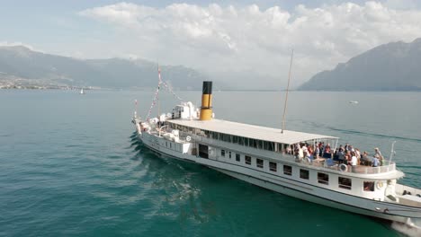 cinematic aerial orbit of a beautiful cruise ship with people on deck on lake geneva, switzerland