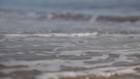 mano colocando un barco de origami en el mar mientras las olas se lo llevan