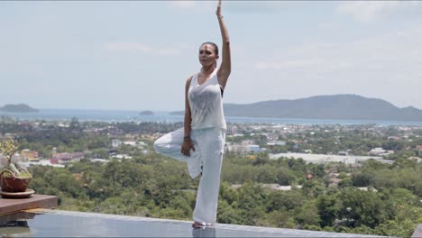 adult woman practicing yoga in poolside against amazing landscape