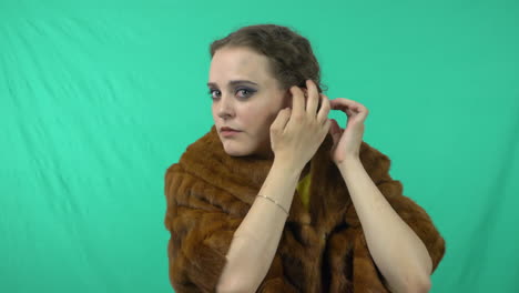 a conscious woman fixing herself while standing against green background - medium close up shot